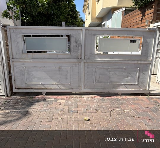שער מתכת צבוע בלבן עם חלונות זכוכית.